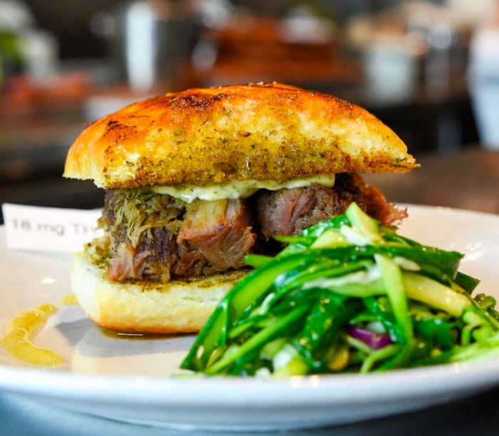 Jerk Oxtail Patty with Infused Coco Bread, Scotch Bonnet Mayo, and Callaloo Slaw
